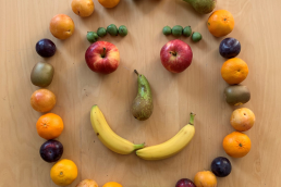 Aus verschiedenen Obstorten wurde ein Gesicht gelegt (Bananen als Mund, Äpfel als Augen etc.).